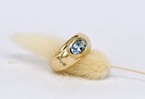 Handgefertigter, moderner Bandring aus Gelbgold von Goldschmiede Stephanie Berger mit hellblauem Aquamarin und seitlich gefassten Brillanten.