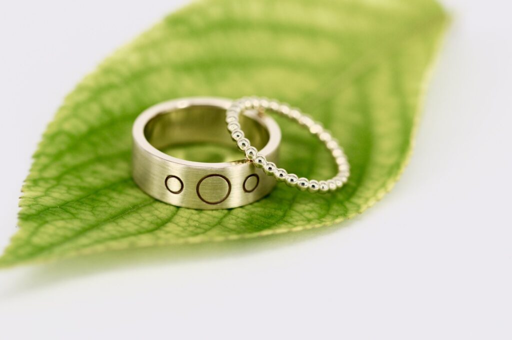 Besonderes Ehering-Paar aus Gelbgold von Goldschmiede Stephanie Berger: Verspielter Kugelring für die Dame und breiter Herrenring mit Präzisions-Lasergravur.