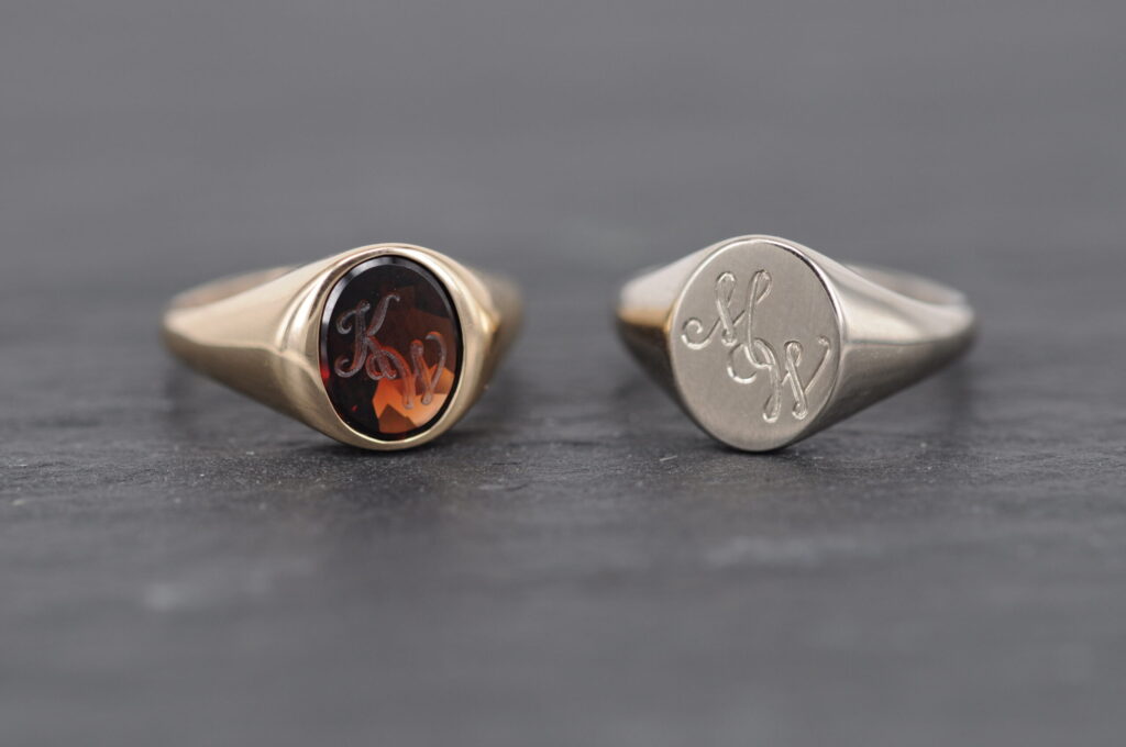 Eheringe als Siegelringe von Goldschmiede Stephanie Berger: Damenring aus Roségold mit tiefrotem Granat und Herrenring aus Weißgold mit eingravierten Initialen.