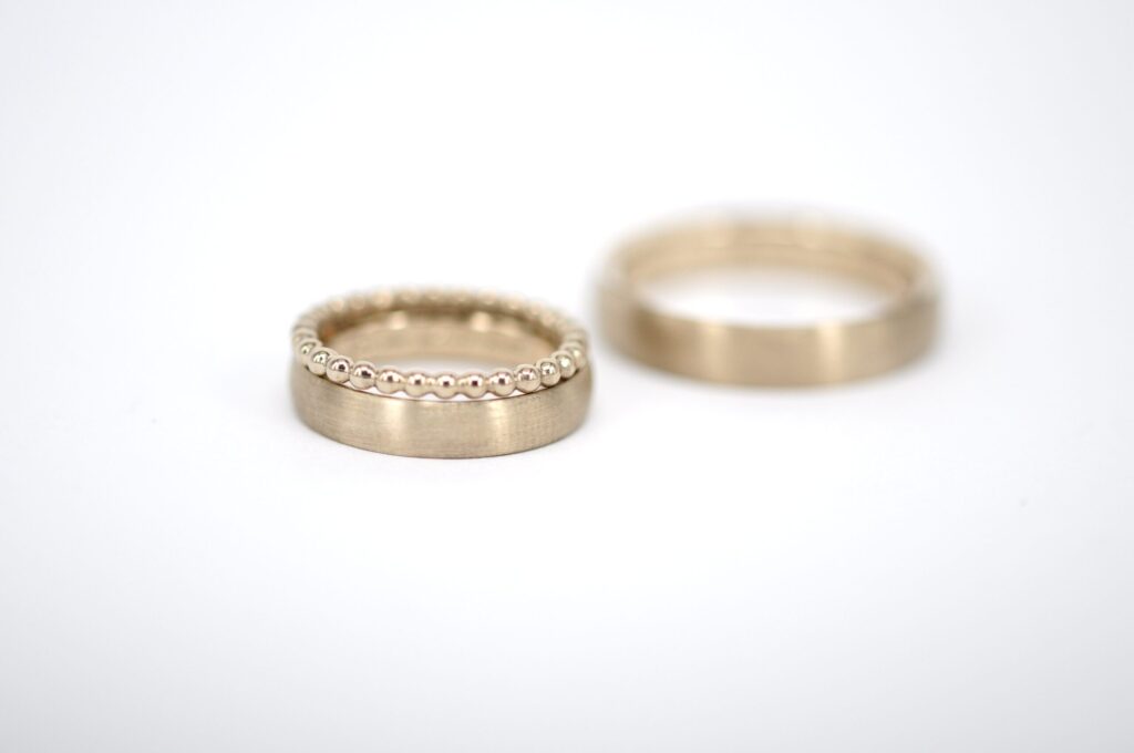 Paar Eheringe aus Haselnussgold von Goldschmiede Stephanie Berger, kombiniert mit einem filigranen Kugelring als Beisteckring für die Dame.