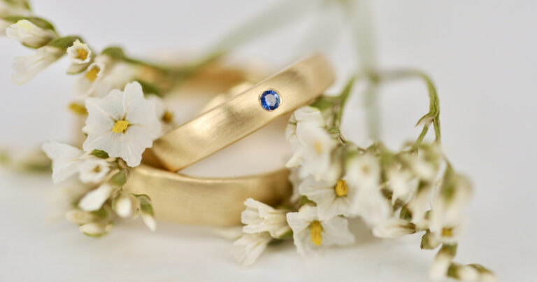 Individuelle Trauringe aus Gelbgold mit blauem Edelstein – gefertigt von der Goldschmiede Stephanie Berger in München.